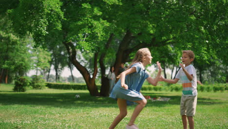 carefree siblings play catch up on beautiful lawn. healthy active childhood