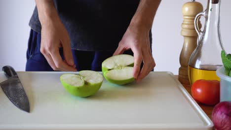 a piece of unpeeled green apple being cut on cubes using sharp kitchen knife