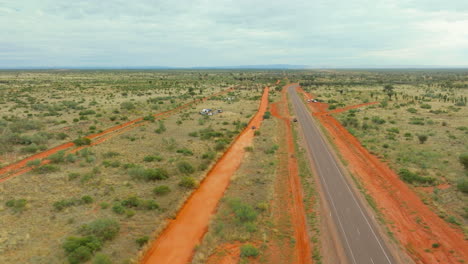 red dirt race track with trophy truck racing alongside highway at finke desert race, 4k drone australia