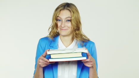 a young woman holding a stack of books embarrassment ulybaetsyavideo photographed in the studio on a