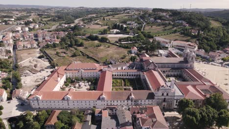 aerial pan shot of the side entrance of alcobaça monastery complex in historic city of portugal
