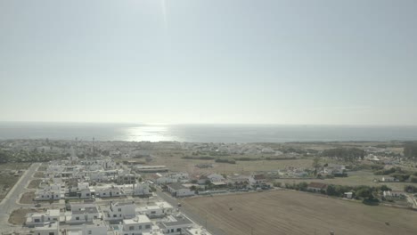 backwards aerial shot over a village by the sea