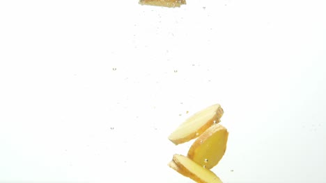 pieces of ginger floating in water with air bubbles, isolated on white background