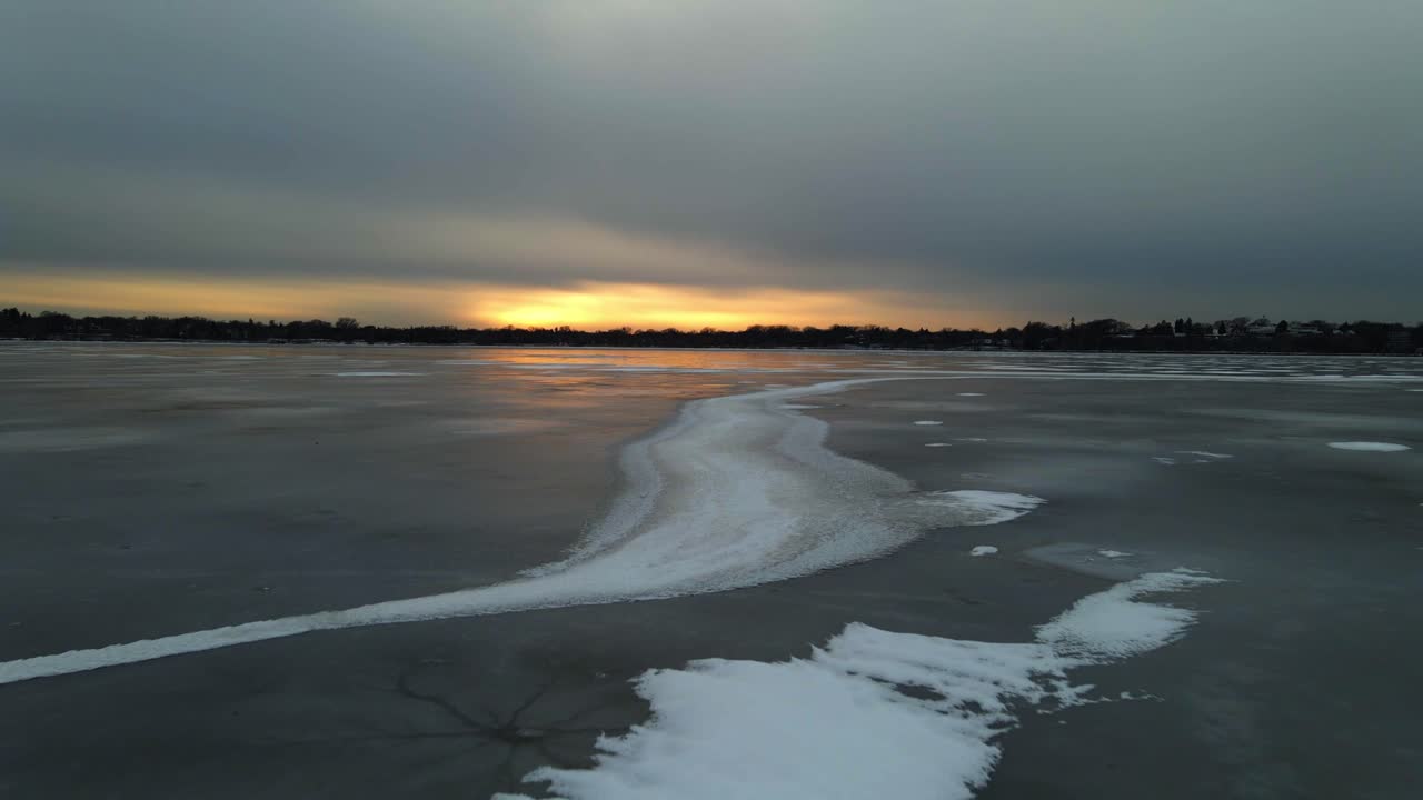 Frozen Lake surface with interesting patterns over the ice and sun setting on the horizon