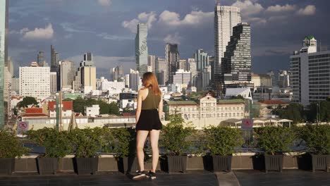 a scenic panorama view of a young beautiful woman looking out over the city skyline of bangkok, thailand