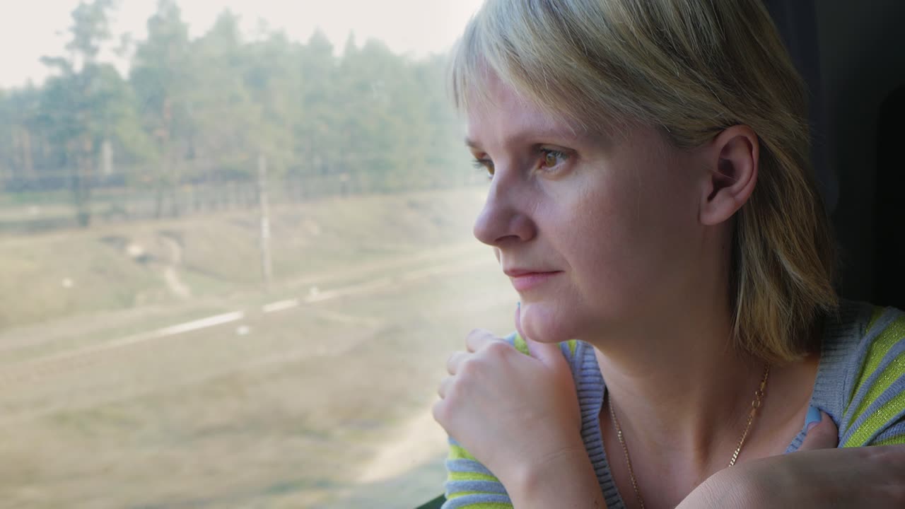 Portrait Of A Young Woman Traveling In A Train Looking Out The Window The Sun's Rays Illuminate Her 