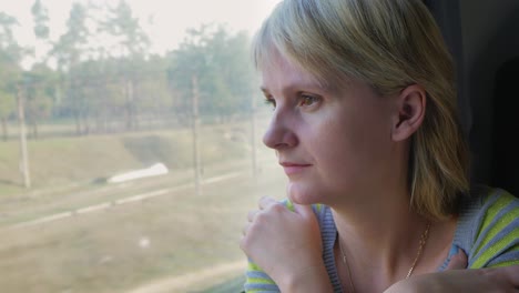 Portrait-Of-A-Young-Woman-Traveling-In-A-Train-Looking-Out-The-Window-The-Sun's-Rays-Illuminate-Her-