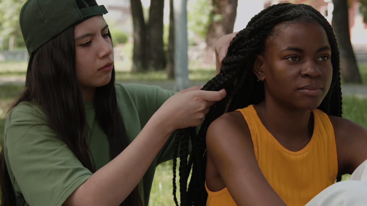Friends styling braided hair in a park