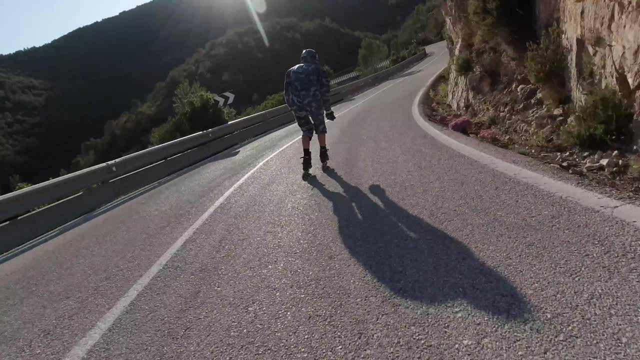 Roller skater taking turns in a mountain road on a sunny day.