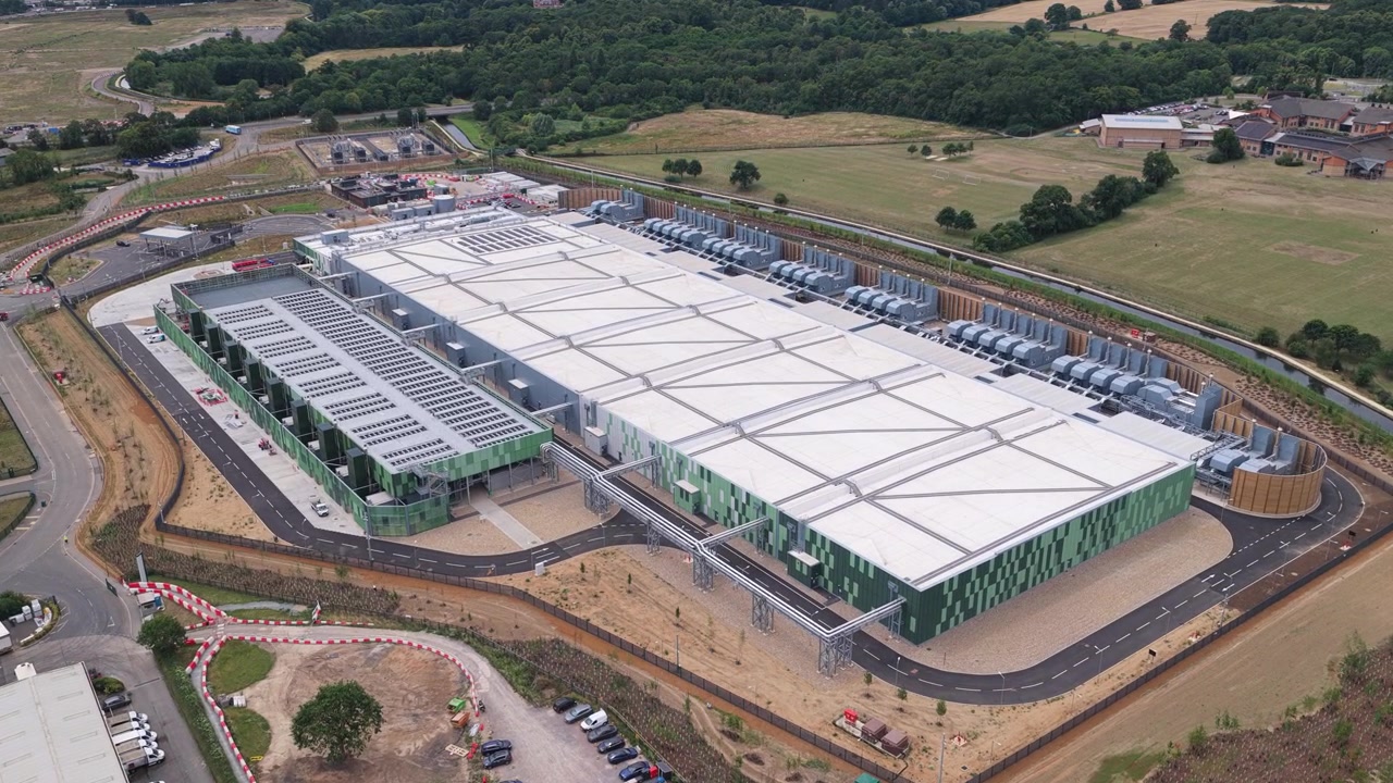 Moderna struttura di data center situata in un paesaggio rurale inglese, che presenta enormi edifici server con sistemi di raffreddamento durante un pomeriggio luminoso e soleggiato per operazioni industriali.