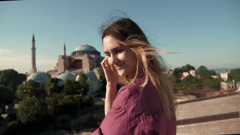 happy young beautiful tourist woman posing, wind blowing in hair at beautiful view of sunny summer hagia sophia, turkey.