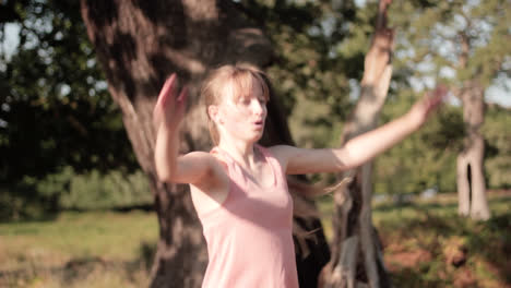 on a sunny day in the park, a young woman doing jumping jacks in front of the tree