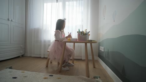 young girl sitting at a table, drawing with colorful crayons. ideal for themes of creativity, childhood development, learning, and art activities in a cozy indoor setting.