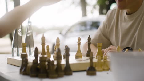 close up of a happy father and son playing chess and giving high five outdoors