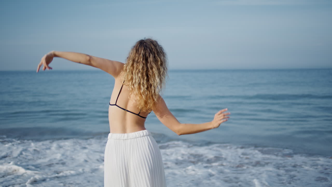 여자 댄서가 해변에서 손을 흔들며 춤을 춘다. 여자 귀여운 움직임