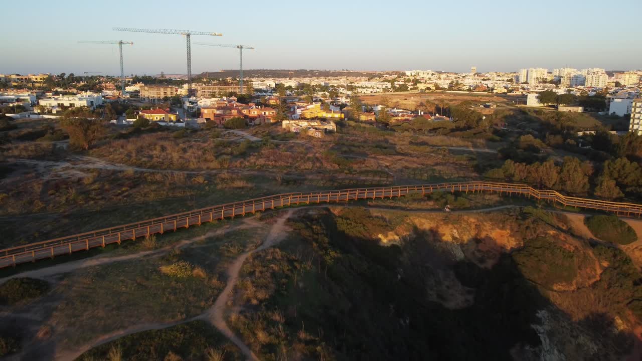 vista aérea, tomas de drones 4k, revelando praia de doña ana, lagos, con un hombre en bicicleta al amanecer, algarve, portugal