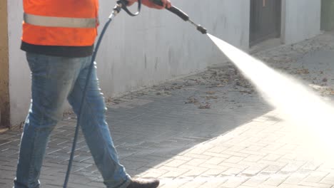 worker cleans the walkway with a pressure washer