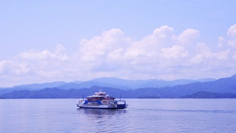 ferry swimming into the distance with mountains on the horizon in costa rican landscape on sunny day with cloudy sky