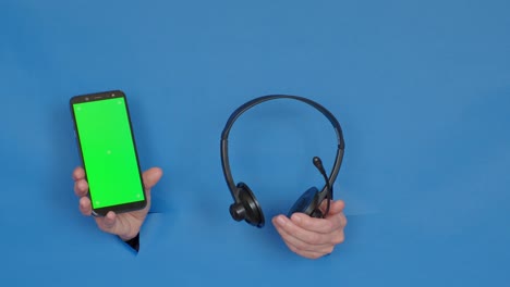 phone with green screen and headphones on blue background