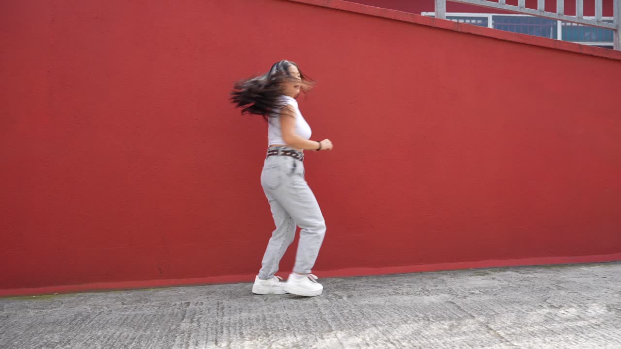 Woman dancing in front of a red wall
