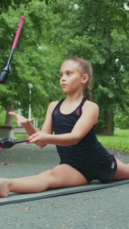young girl practicing flexibility and balance on a yoga mat in a serene outdoor park setting, focusing on stretching techniques for dance and fitness