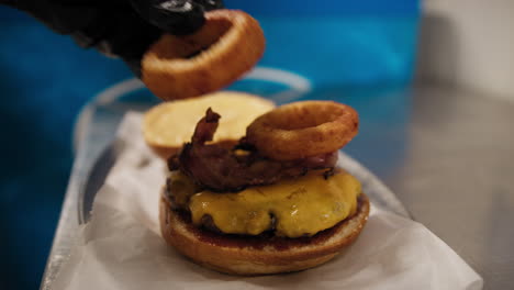 chef adding onion rings to complete the gourmet burger