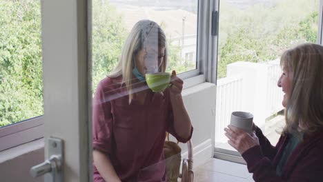 mother and daughter talking to each other while drinking coffee at home