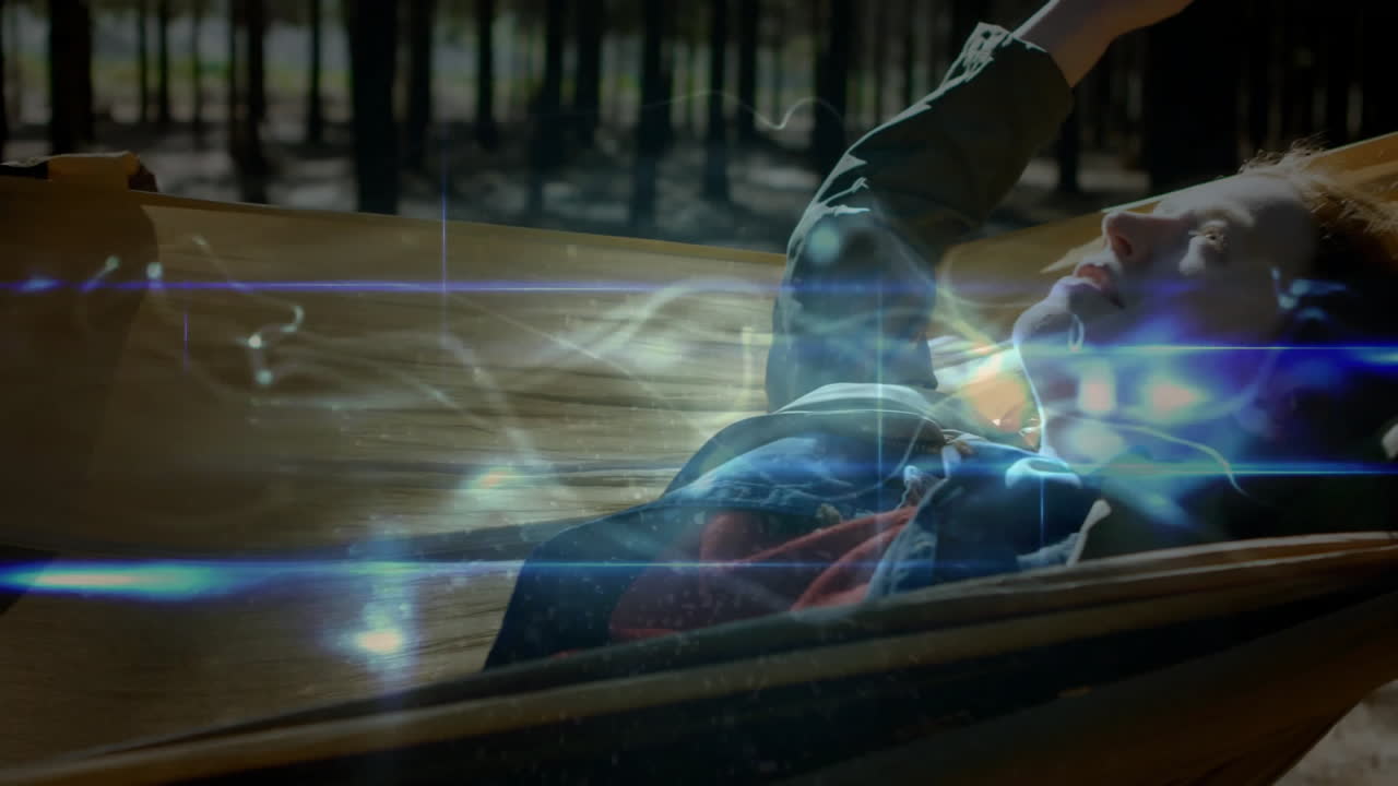 Woman reclining in forest hammock for technology demo, featuring swirling digital light animations