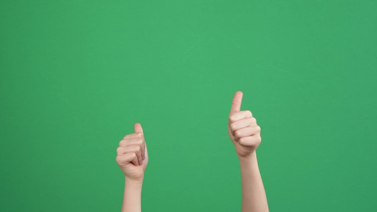 아이가 누군가를 가리키고, 일어서서, 초록색 스크린 배경에 두 손 엄지손가락을 보여주고 있습니다.