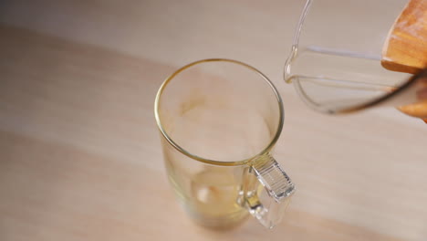 Pouring-coffee-from-a-glass-French-press-with-a-wooden-handle-when-viewed-from-the-front-and-top-on-a-tall-glass-captured-by-pouring-coffee-in-slow-motion-capture-at-120-FPS