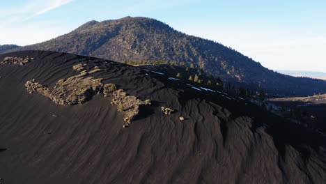 Duna-De-Arena-Negra-Con-Montaña-Volcánica-En-El-Cráter-De-La-Puesta-Del-Sol,-Asta-De-Bandera---Disparo-Aéreo-De-Drones