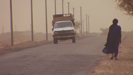 Una-Persona-Touareg-Camina-Por-Una-Carretera-A-Través-Del-Desierto-Del-Sahara-En-Malí-Durante-Una-Tormenta-De-Viento