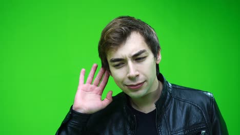 hombre blanco con chaqueta de cuero escuchando a escondidas sobre el fondo de la pantalla verde.