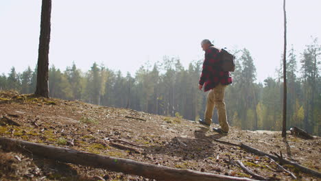 backpacking and enjoying beauty of nature at autumn day middle-aged man is hiking and rising on top of hill looking around