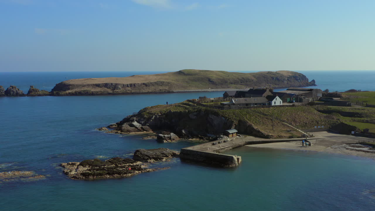 Aerial drone pan capturing Portmuck Harbour and Island on a sunny day. Northern Ireland.
