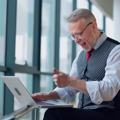 freelance senior man working on a laptop. mature man becomes happy after doing a successful job on a computer at home.
