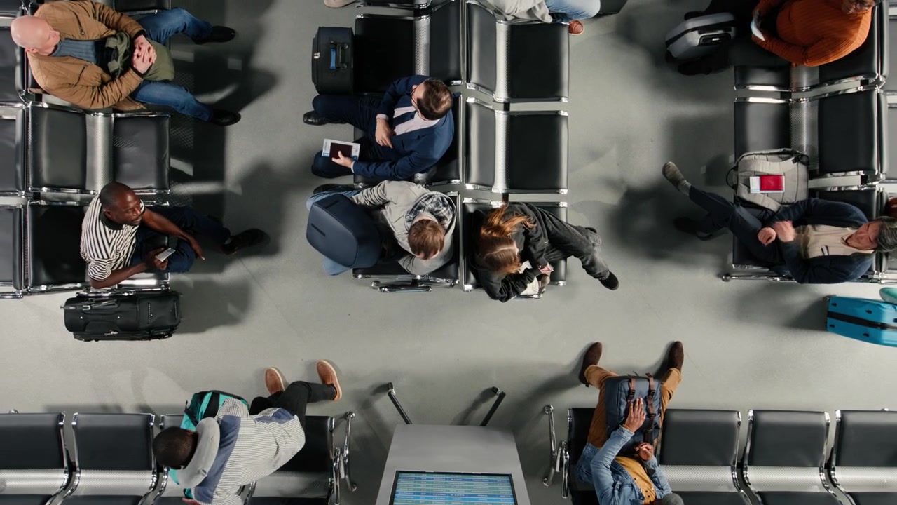 Top down view of busy airport terminal with people checking departure board