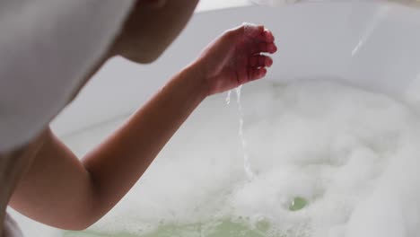 african american woman touching water in the bath tub in the bathroom at home