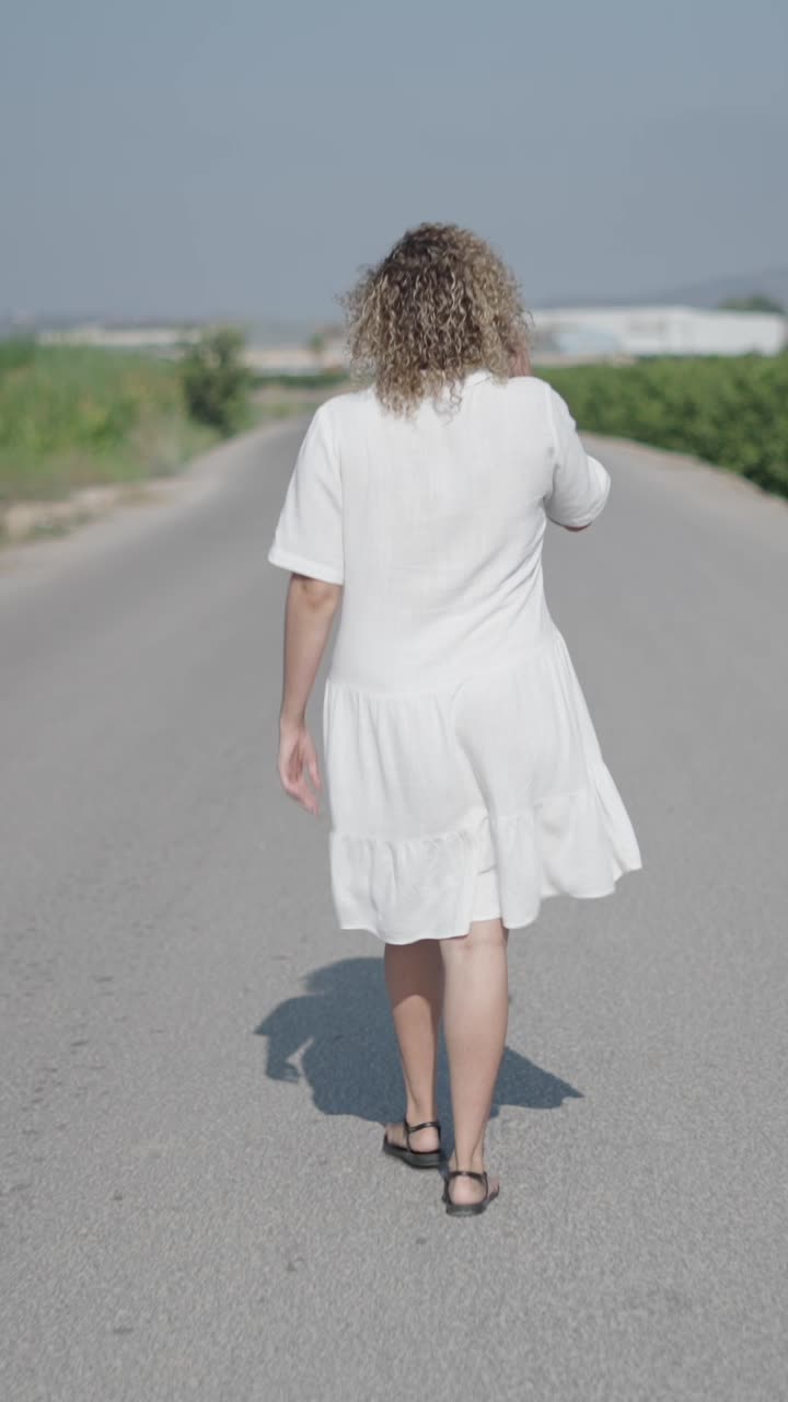 Donna in abito bianco che cammina su una strada
