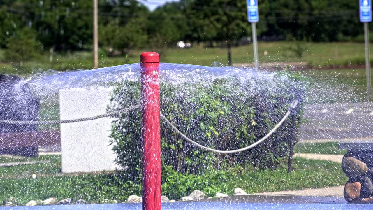 Water sprays joyfully from a vibrant red fountain