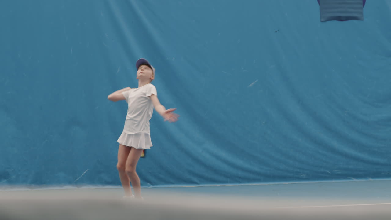 Young Girl Throwing And Hitting Tennis Ball