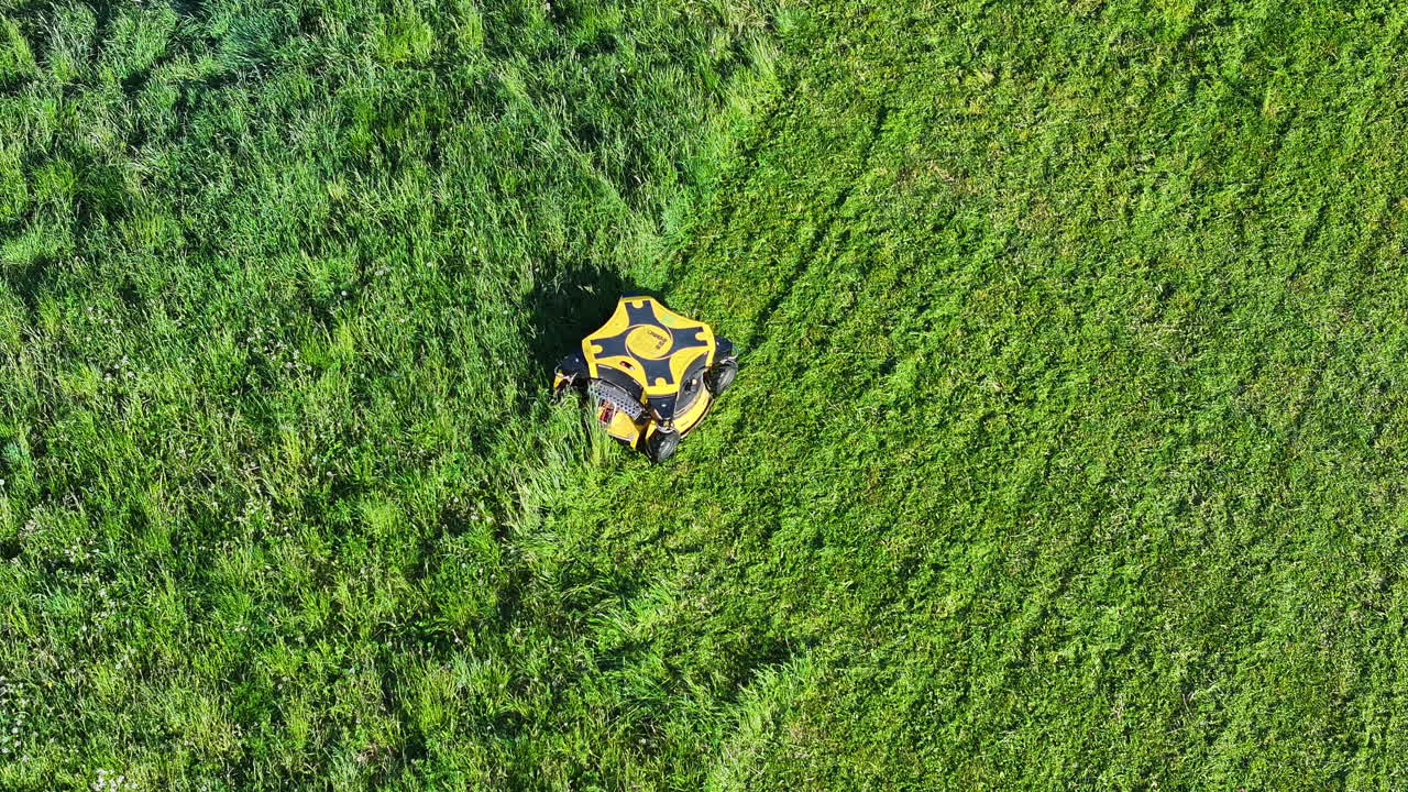 cortadora de césped robótica en césped verde en un soleado día de verano, vista desde arriba, disparo de avión no tripulado