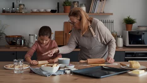 caucasian girl preparing homemade cookies with grandmother