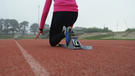 Rear-view-of-female-athlete-taking-starting-position-on-running-track-4k
