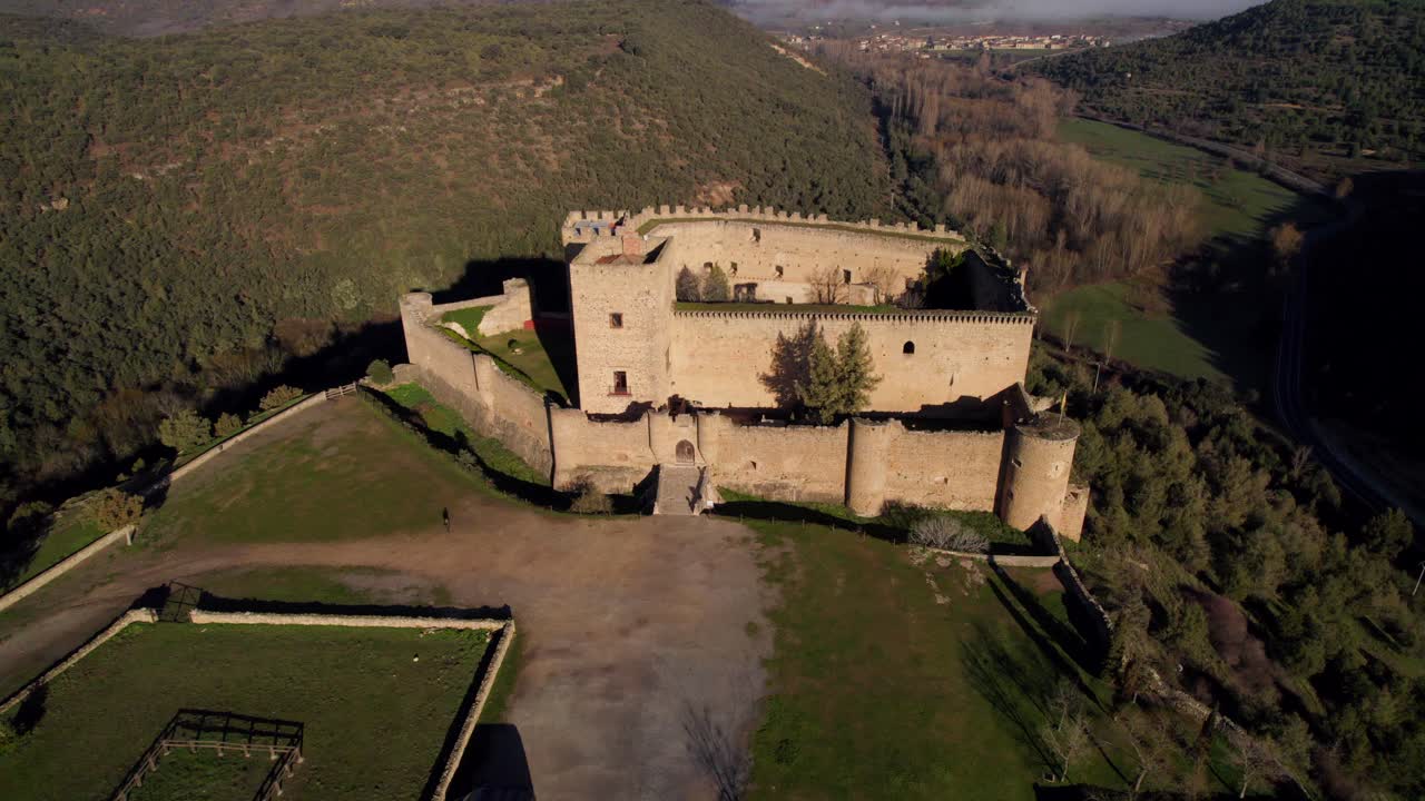 dolly aéreo centrado en el castillo medieval de piedra en el pueblo español de pedraza al amanecer.