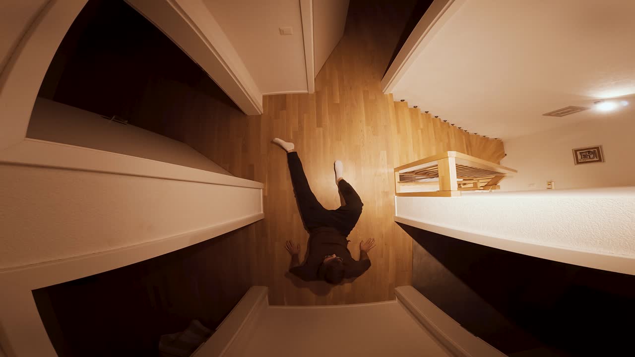 A man collapses to the floor in fear, backing away from something unseen inside the room, filmed from above