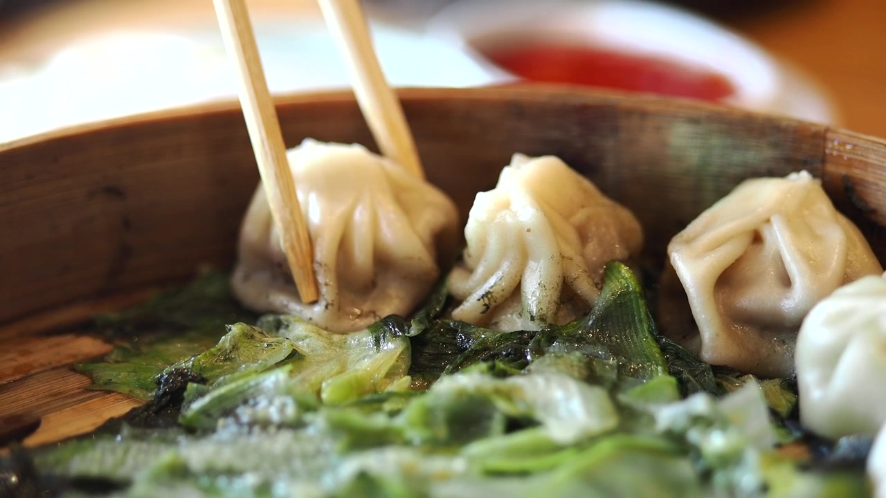 Chopsticks Picking Up a Steamed Dumpling from a Bamboo Steamer