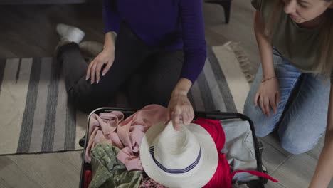 Best-friends-put-dresses-and-hats-into-suitcase-for-vacation