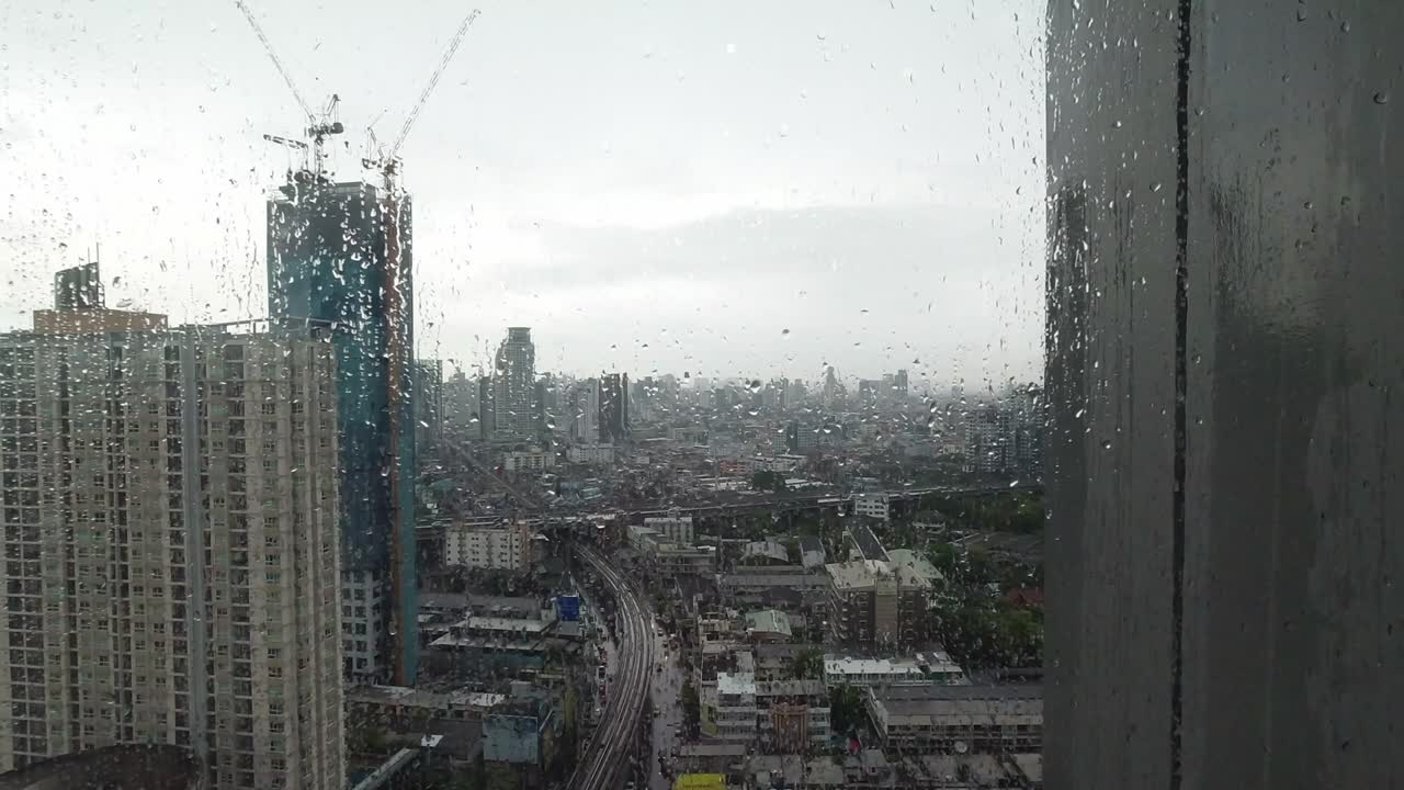 la lluvia cae por la ventana. vista aérea. la lluvia fuera de la ventana de la sala de estar en la temporada de lluvias en bangkok, tailandia. la ventana exterior está borrosa por la lluvia del edificio de la ciudad y la carretera y el cielo.