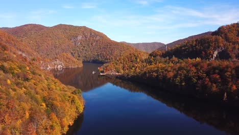 Tiro-De-Drone-Deslizante-Del-Lago-Tarnita,-Rumania,-Rodeado-De-Coloridos-árboles-De-Otoño